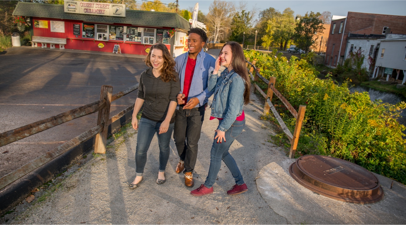 Three friends laughing together outside of an ice cream stand.