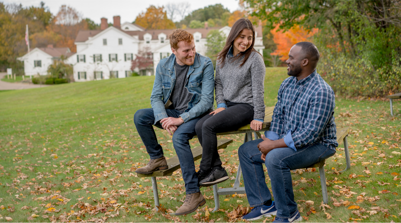 three people sitting in a park, talking