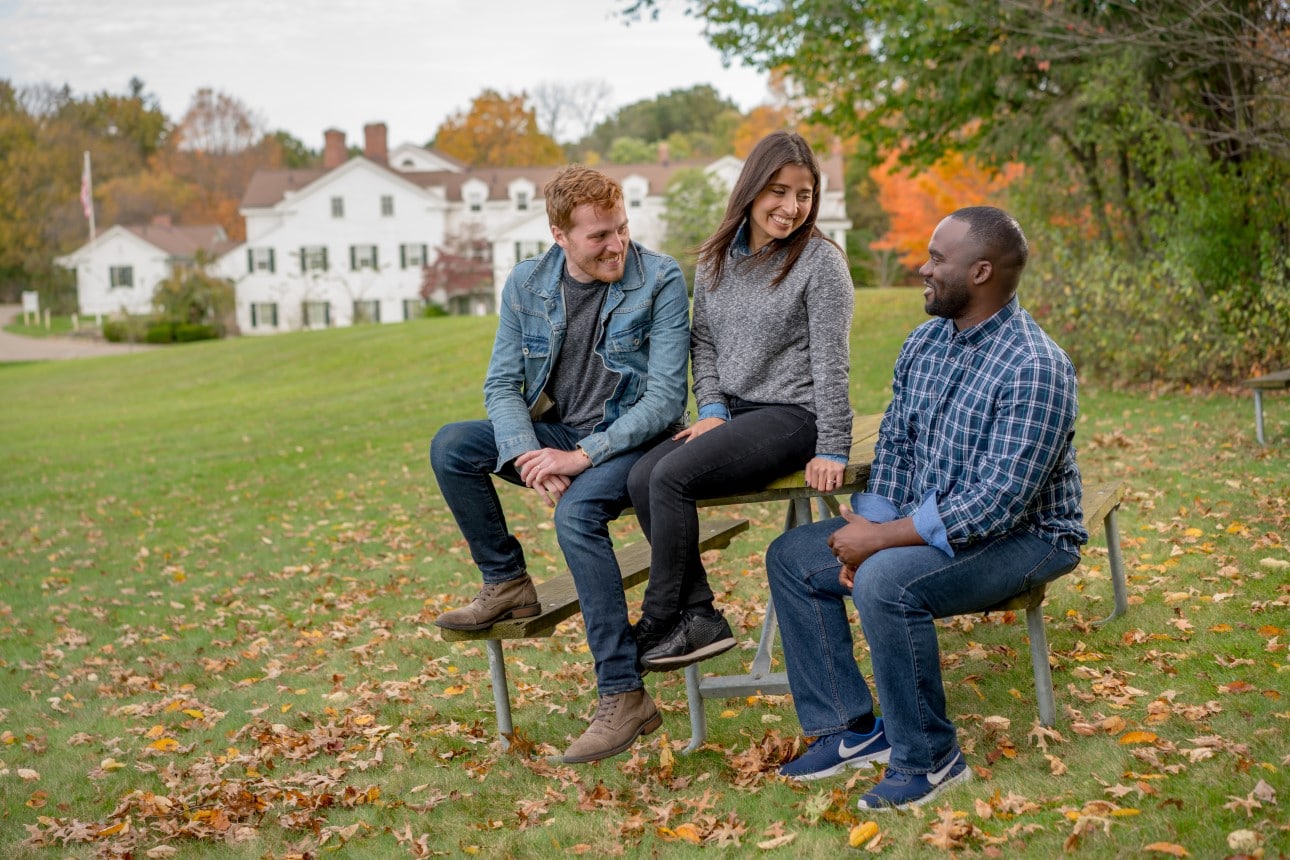 three people sitting in a park, talking