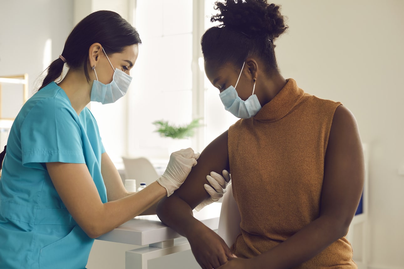 Doctor preparing a young woman’s arm for the COVID-19 vaccine