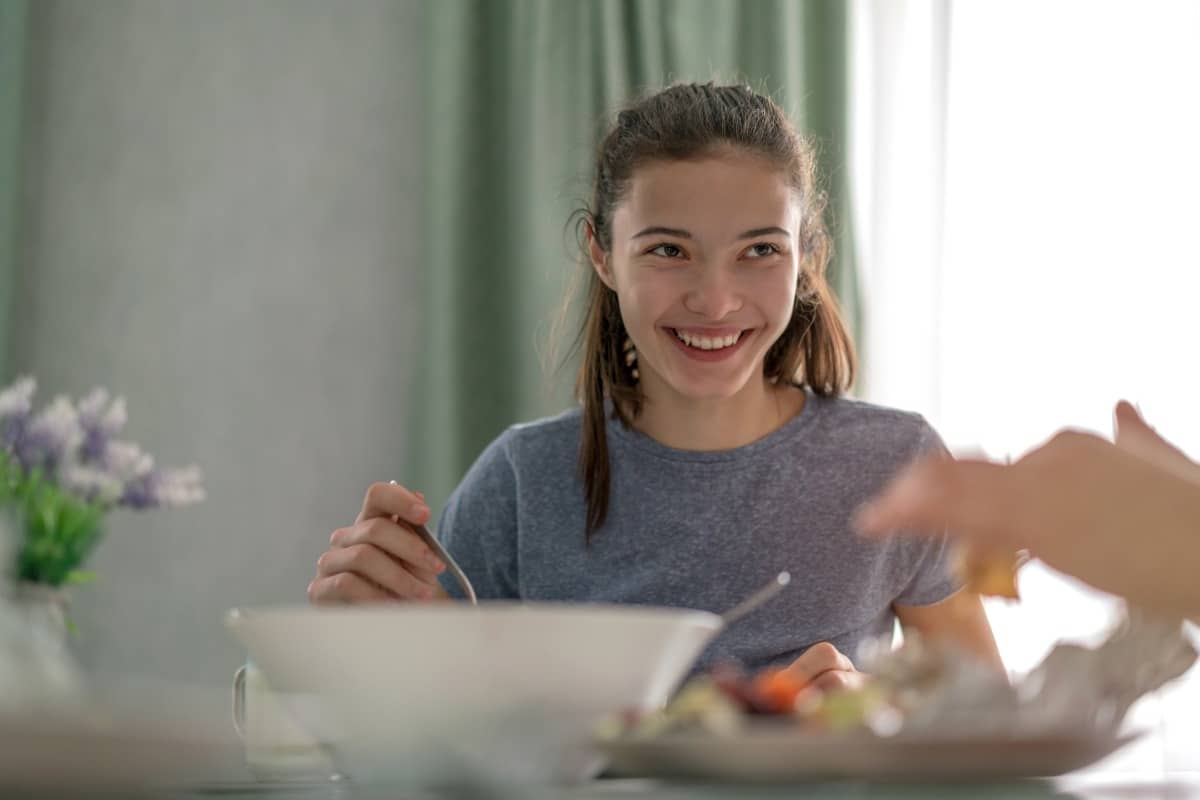 Girl at table smiles during family dinner conversation