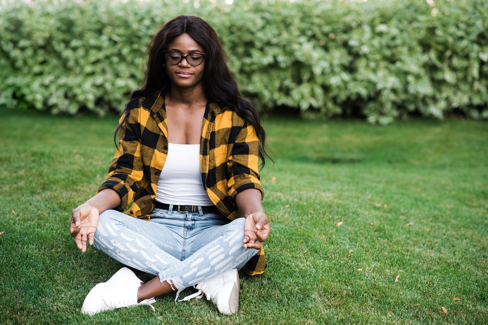 Young woman meditating in park for her mental health