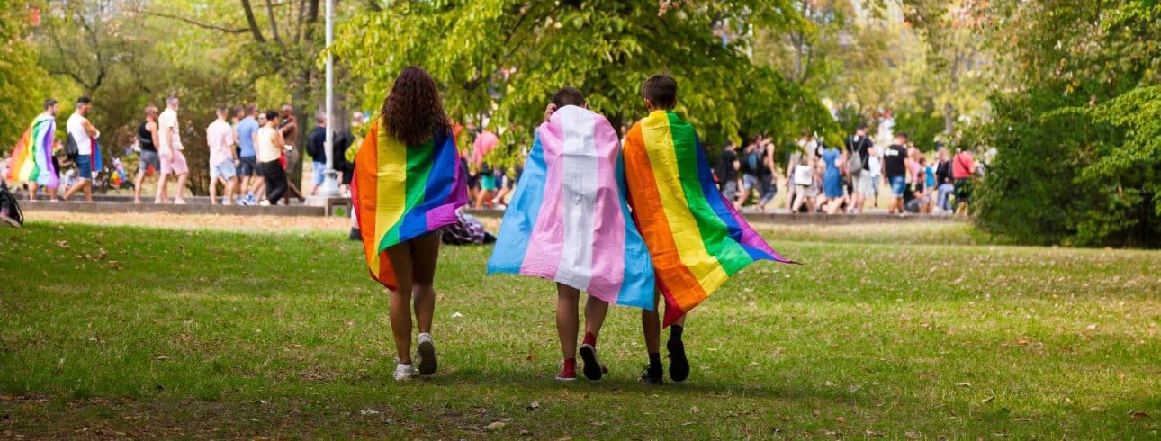 Three people draped in PRIDE flags at one of the PRIDE events in Ohio