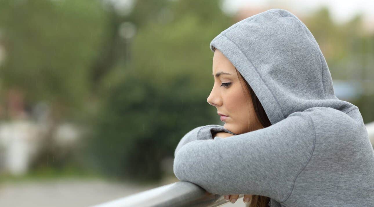 Sad teenage girl looking down from a balcony